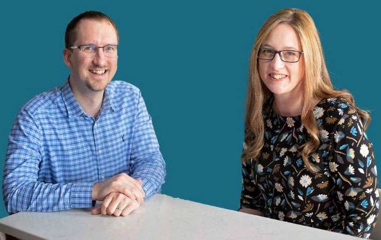 Mike and Liz at table websize Mike and Liz sitting at a table, looking at the camera